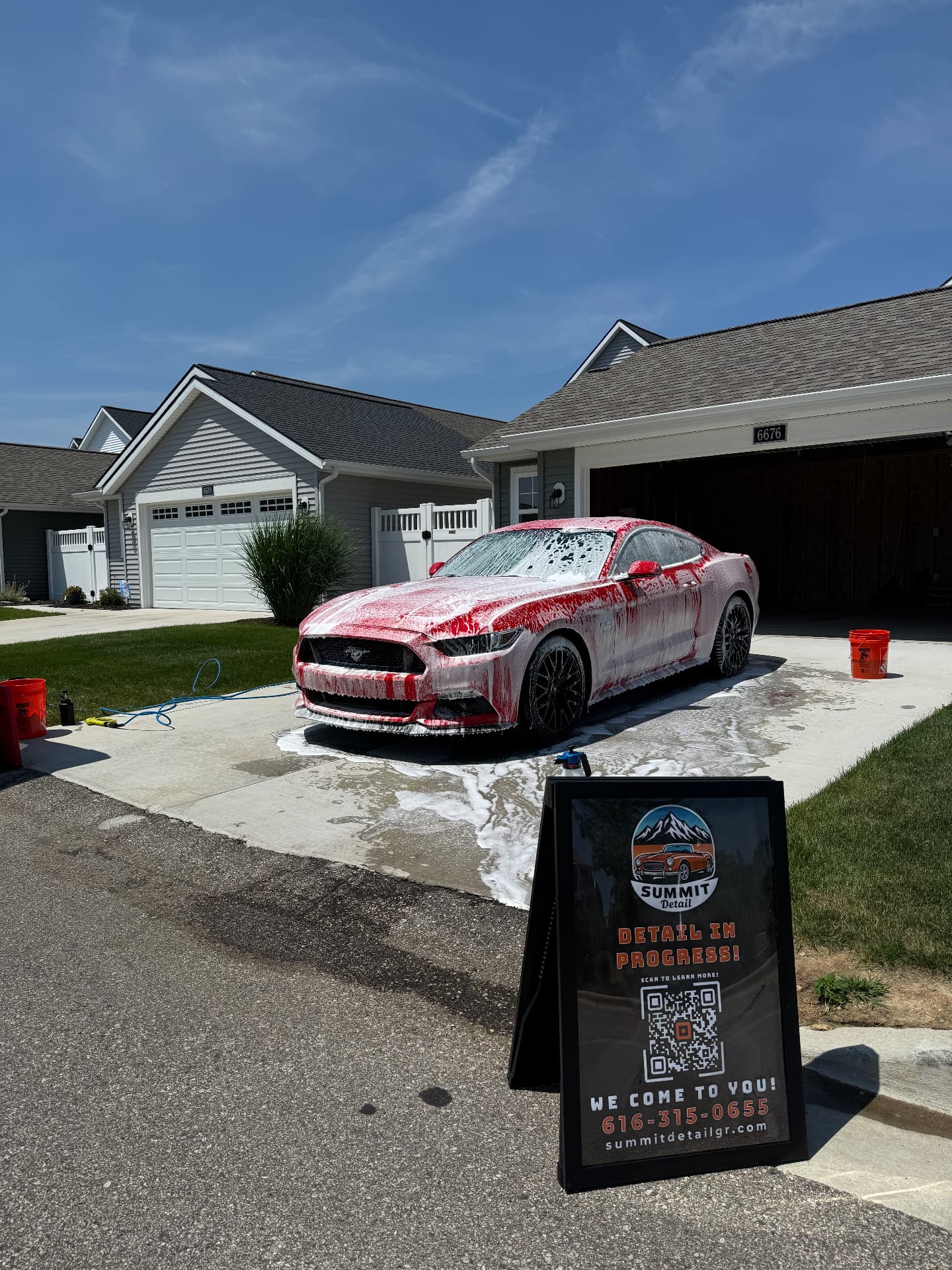 Red Ford Mustang being hand washed in a driveway with Summit Detail signage
